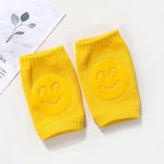 Two yellow knee pads with smiley face designs on a white background.