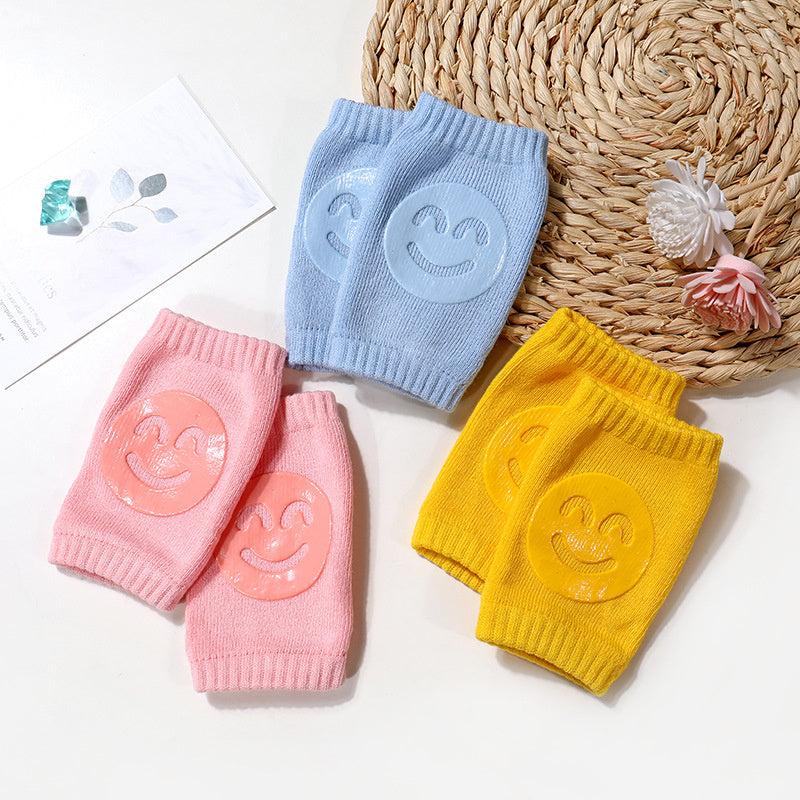 Three colorful knee pads with smiley face designs on a textured surface.