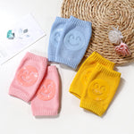 Three colorful knee pads with smiley face designs on a textured surface.