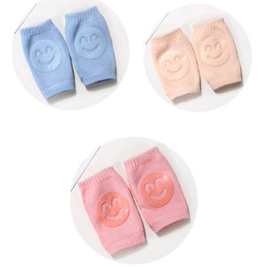 Set of baby knee pads in blue, pink, and peach on a white background