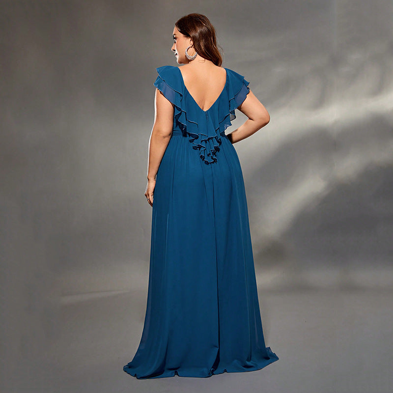 Woman wearing a blue evening gown with ruffled details on a gray background