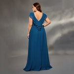 Woman wearing a blue evening gown with ruffled details on a gray background
