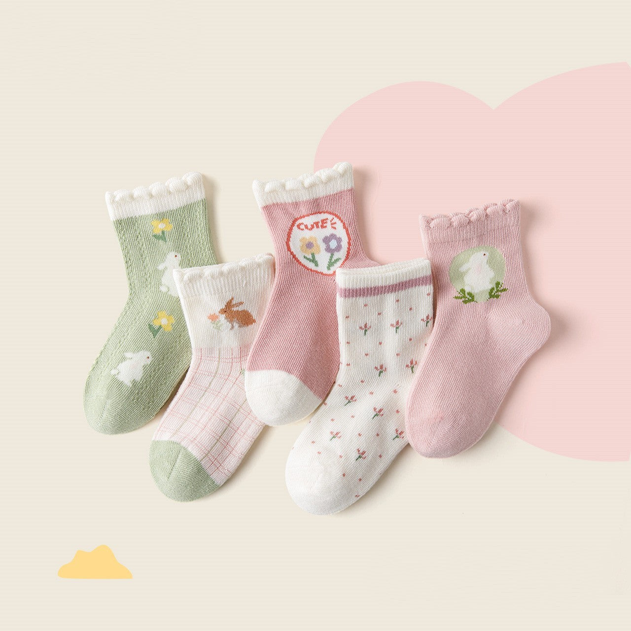Set of five children's socks with various patterns on a light pink background