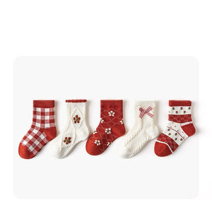 Five pairs of red and white patterned socks on a white background