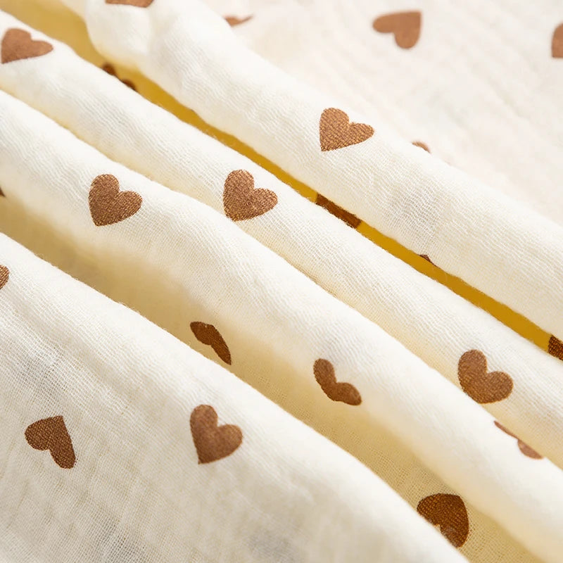 Sheer fabric with small brown hearts on a beige background