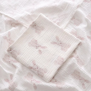 Stack of white fabric swaddles with pink floral patterns