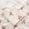 White baby blanket with brown teddy bear patterns on a matching white pillow.