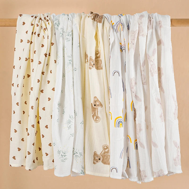Set of four baby swaddle blankets with various patterns on a beige background