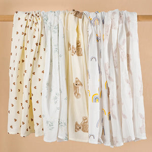 Set of four baby swaddle blankets with various patterns on a beige background