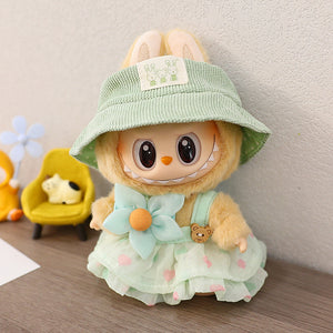 Plush toy with a green hat and light blue dress on a wooden surface.