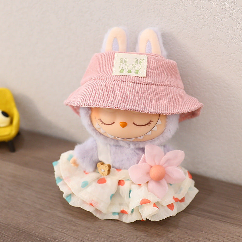 Toy figure with a pink hat and floral skirt on a wooden surface
