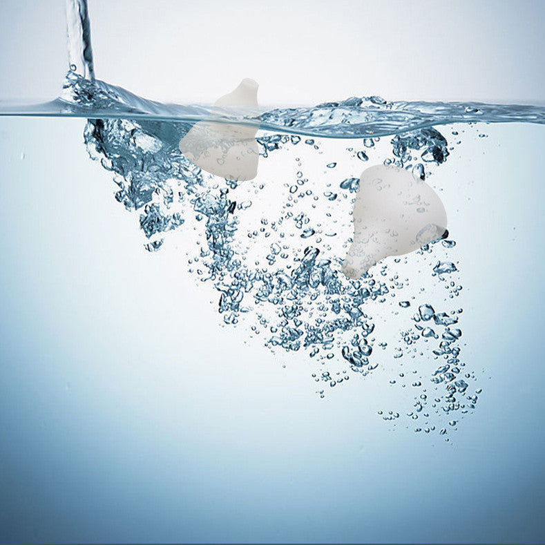 Two white objects, possibly eggs, floating on water with bubbles.