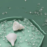 Two white silicone funnels on a green surface with clear gel-like substance around them.