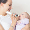 Woman holding a baby and using a device, with a plain background