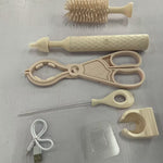 Collection of baby care items including brushes, scissors, and a USB cable on a light gray surface.