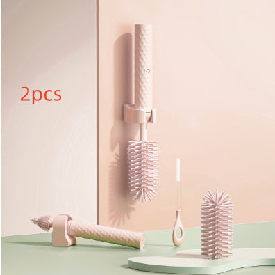Two pink hairbrushes with a holder on a light green surface and pastel pink background.