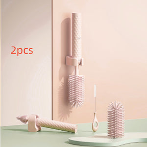 Two pink hairbrushes with a holder on a light green surface and pastel pink background.