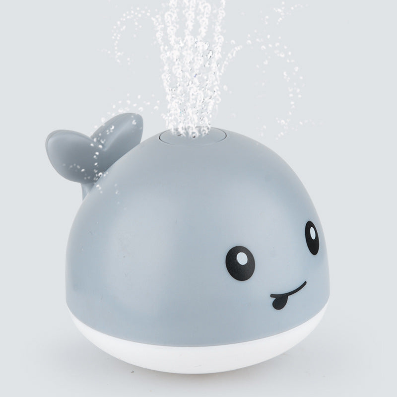 Gray whale-shaped bath toy with water sprouting from its mouth on a light gray background