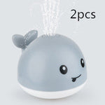 Two gray whale-shaped bath toys with a white base on a light background.