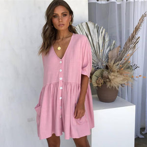 Woman wearing a pink dress standing in front of decorative plants.