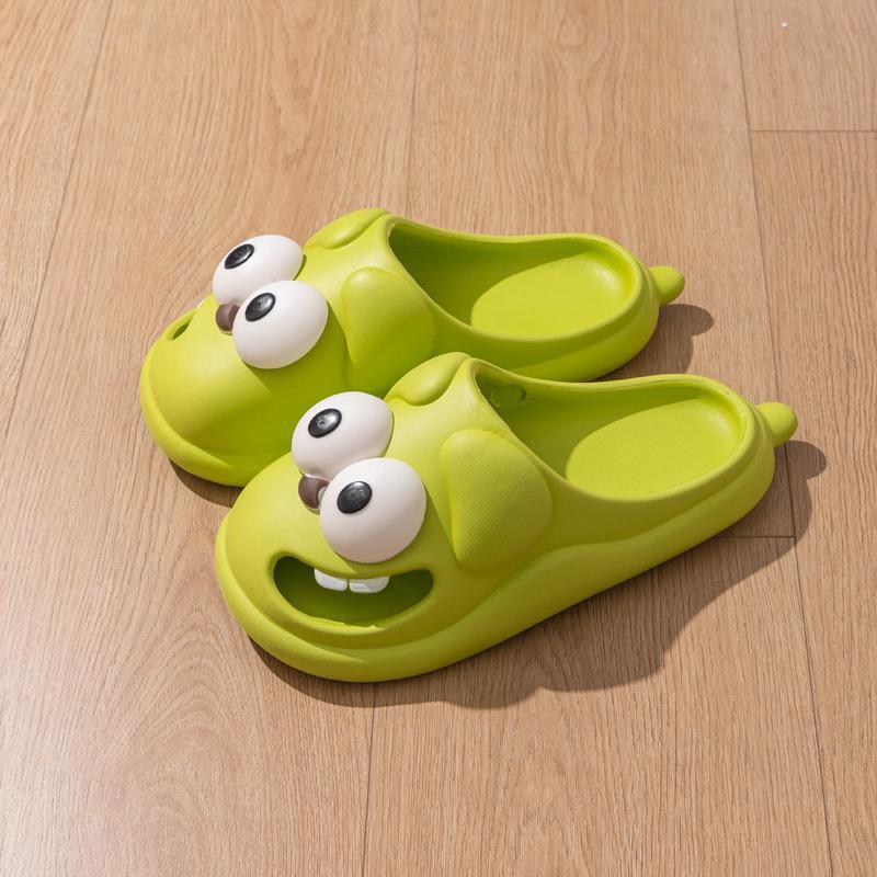 Green cartoonish slippers with googly eyes on a wooden floor