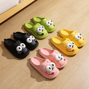 Set of colorful cartoon slippers with googly eyes on a wooden floor.