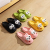 Set of colorful cartoon slippers with googly eyes on a wooden floor.