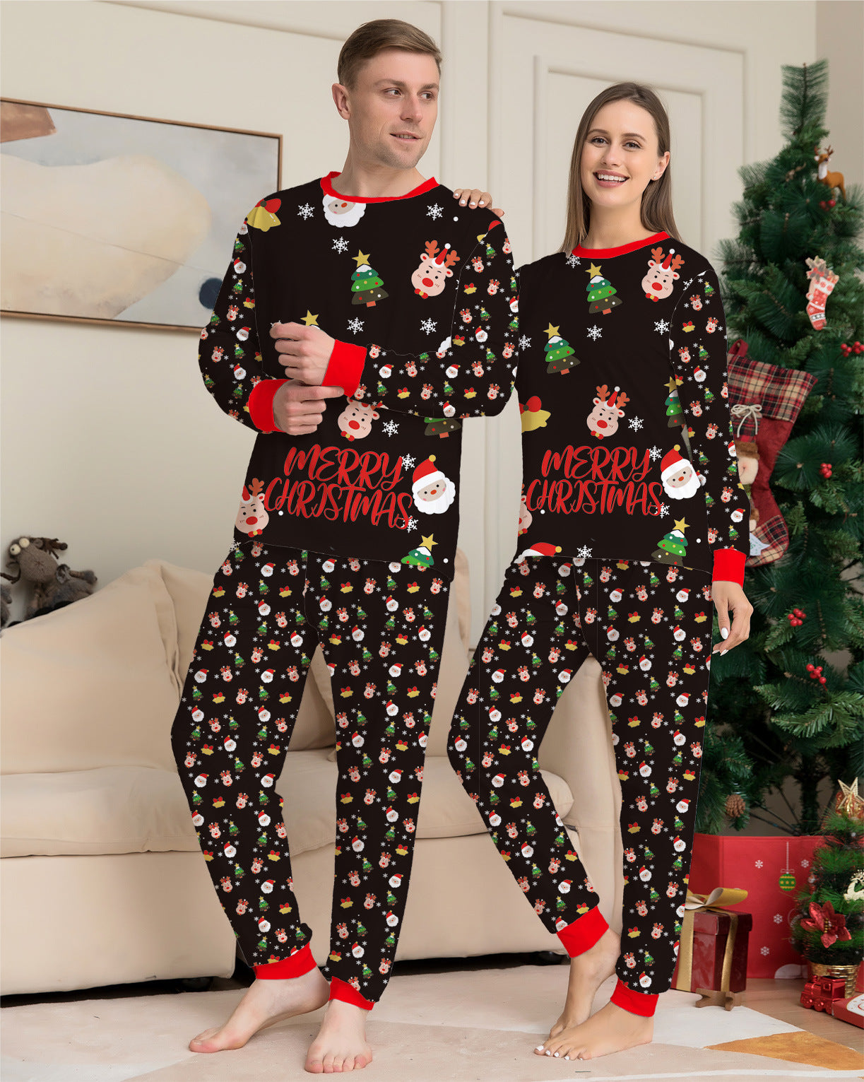 Two people wearing matching Christmas-themed pajamas in a living room with a decorated tree.