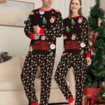 Two people wearing matching Christmas-themed pajamas in a living room with a decorated tree.