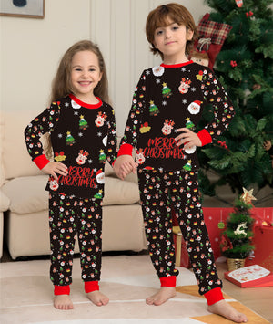 Two children wearing Christmas-themed pajamas in a living room with a decorated tree.