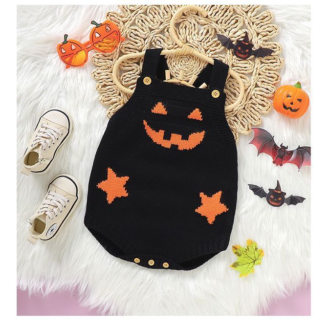 Black Halloween-themed baby romper with orange accents on a white surface with decorative items.