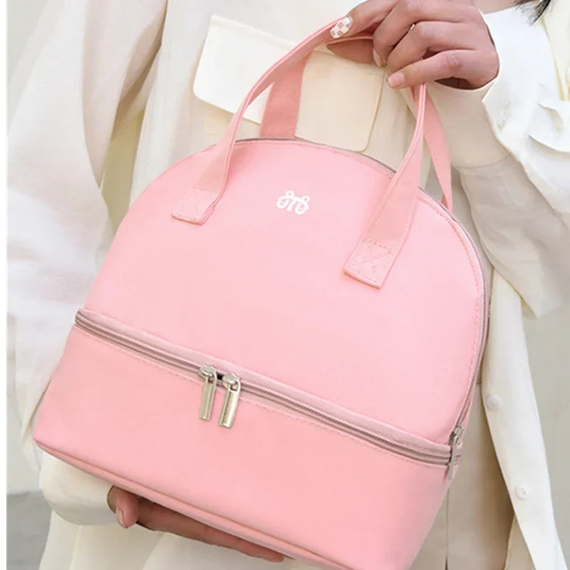 Pink handbag with a brand logo held by a person wearing a white outfit.