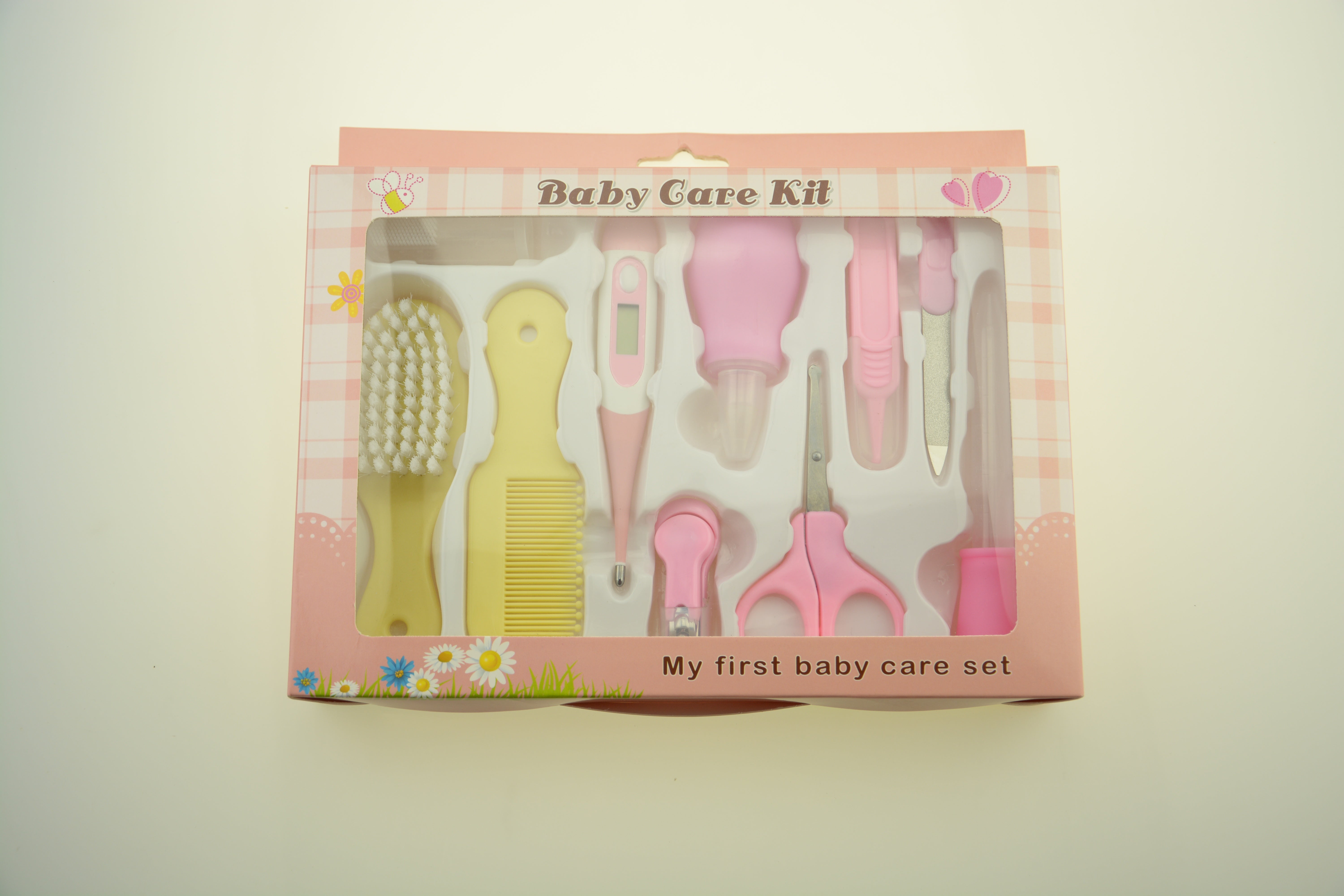 Baby care kit with various tools in a pink box on a light background