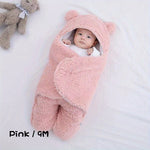 Baby wrapped in a pink fluffy swaddle with bear ears on a white background