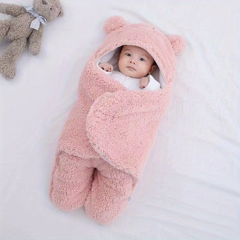 Baby wrapped in a pink fluffy swaddle with a teddy bear on a white background