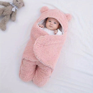 Baby wrapped in a pink fluffy swaddle with a teddy bear on a white background