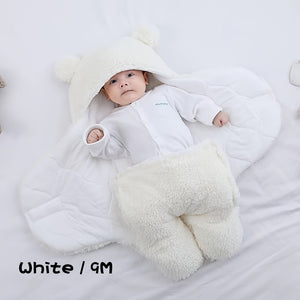 Baby wrapped in a white fluffy blanket on a light gray background