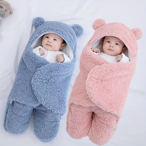 Two babies wrapped in blue and pink bear-shaped swaddles on a white background