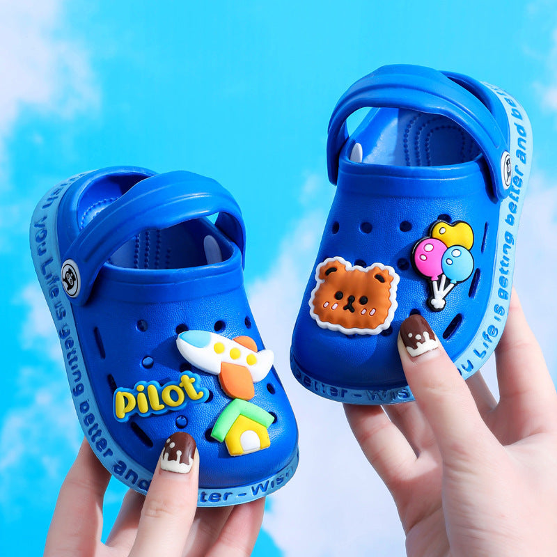 Blue children's clogs with decorative stickers held by a hand against a blue background