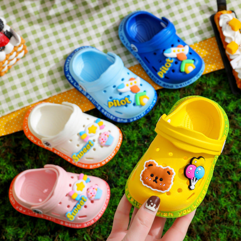 Colorful children's clogs with cartoon designs on a green checkered fabric background.
