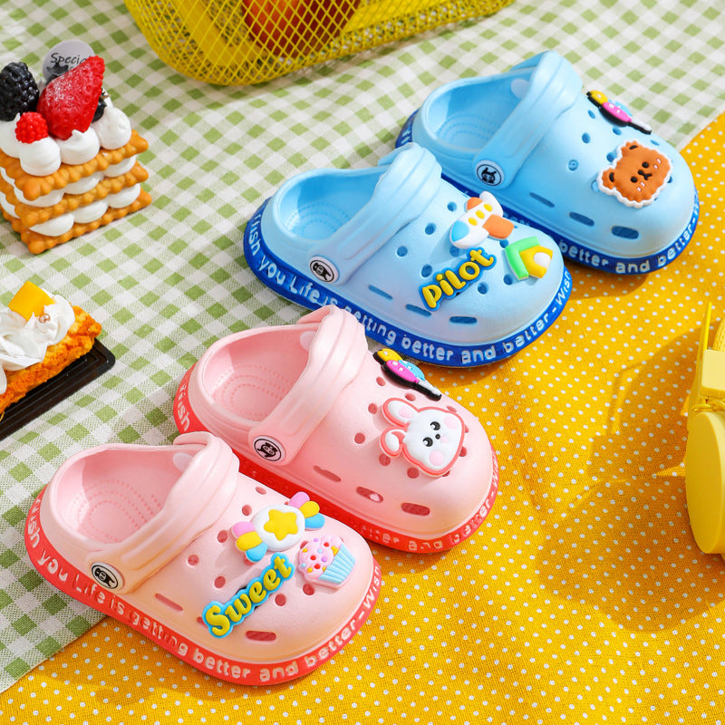 Pair of pink children's clogs with cartoon character design on a yellow and green checkered background.