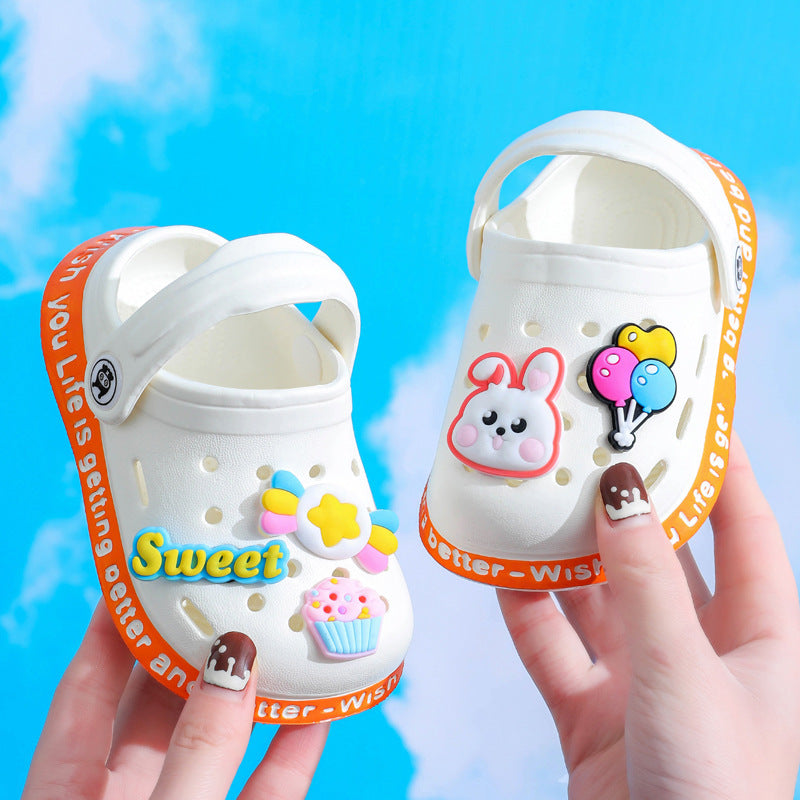 White children's sandals with decorative elements held against a blue background
