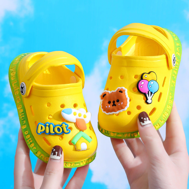 Yellow children's shoes with cartoon designs held against a blue sky background