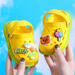 Yellow children's shoes with cartoon designs held against a blue sky background