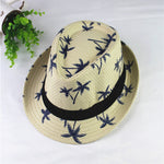 Beige straw hat with blue floral patterns and a black band on a white background
