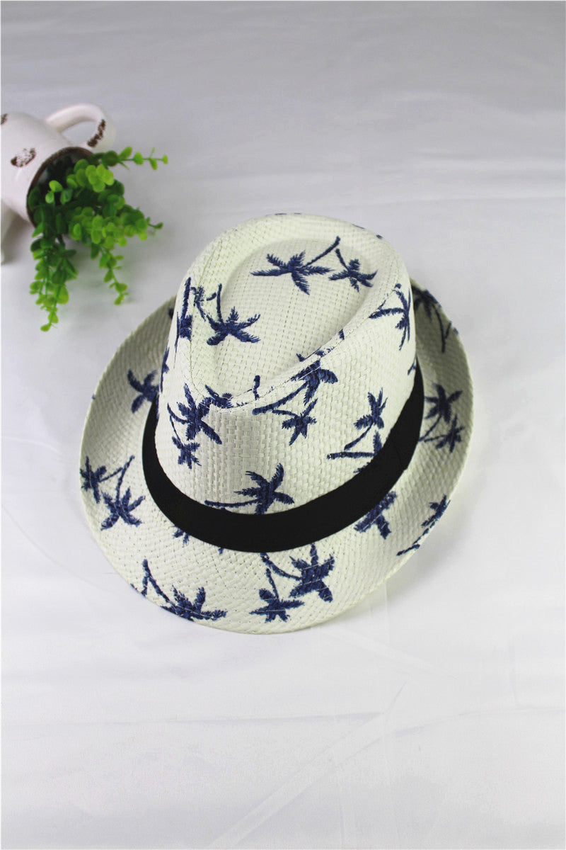 White straw hat with blue floral patterns and a black band on a light gray background.