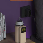 Milk warmer with night light on a shelf next to books, with a purple wall in the background.