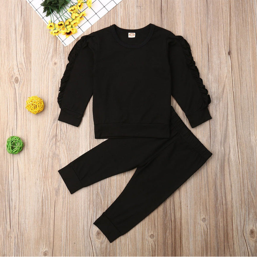Black outfit with ruffled sleeves on a wooden surface