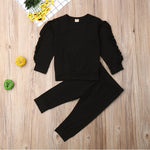 Black outfit with ruffled sleeves on a wooden surface