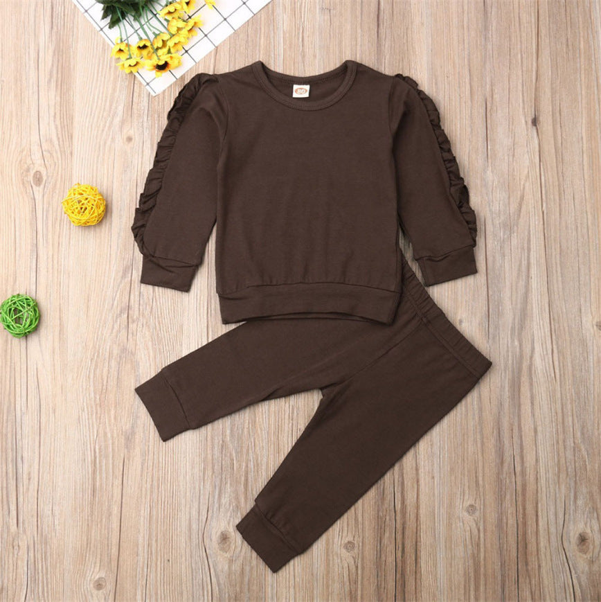 Brown sweatshirt and pants set on a wooden surface with decorative elements.